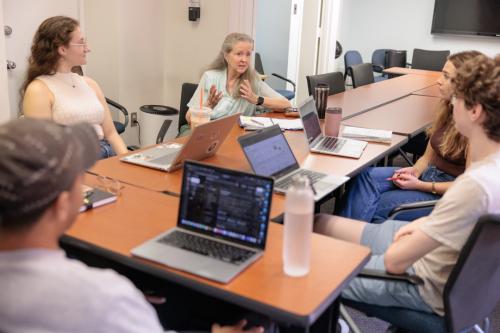 Lynn Offerman seated at a shared table in a classroom with PhD students